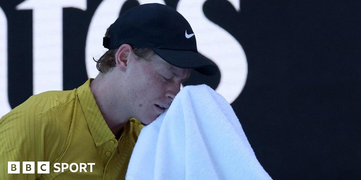 Jannik Sinner wipes his face with a towel