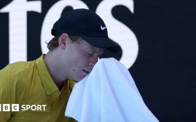 Jannik Sinner wipes his face with a towel